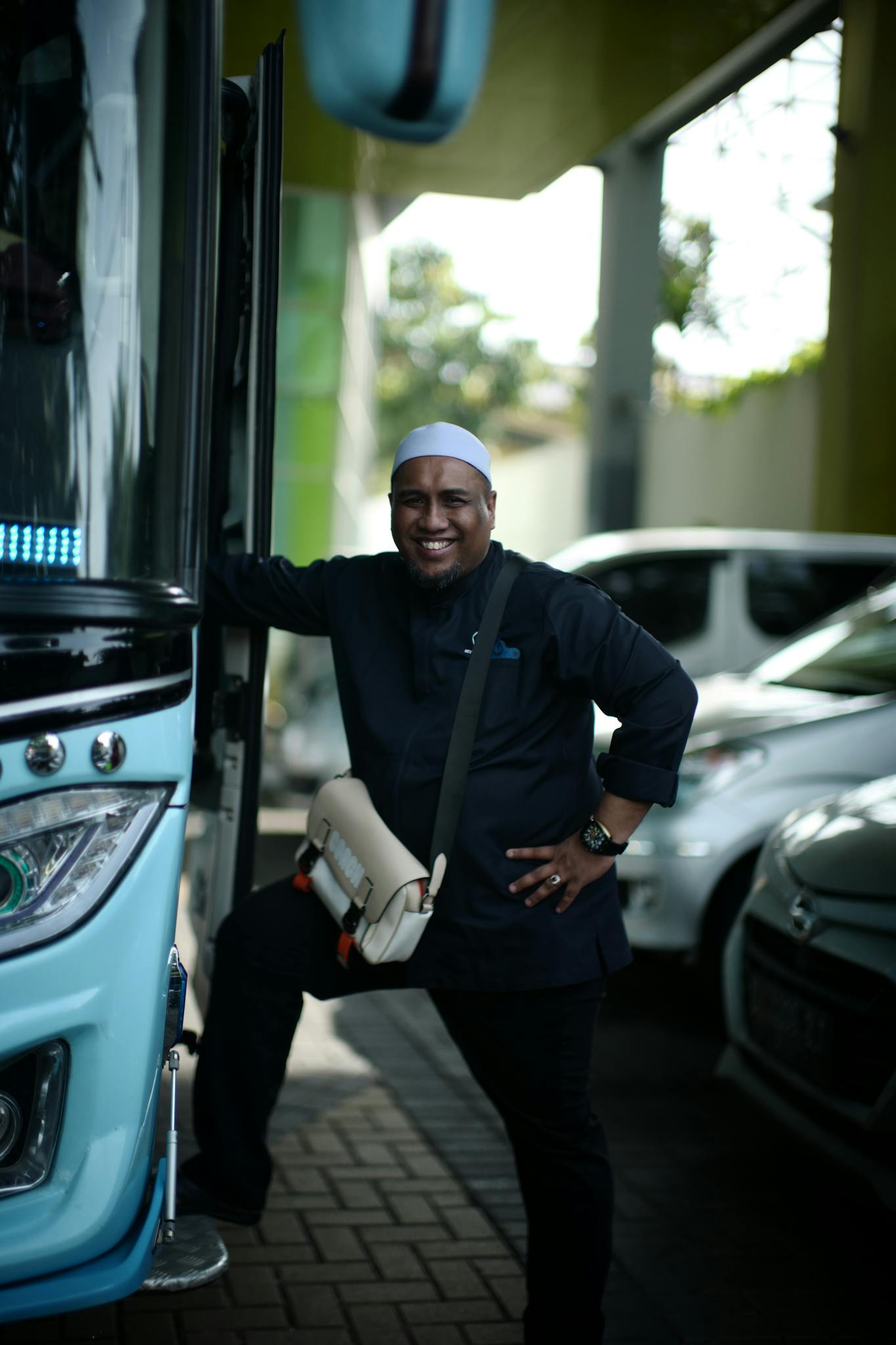 Cheerful bus driver posing at Jakarta terminal, showcasing his profession with a bright smile.